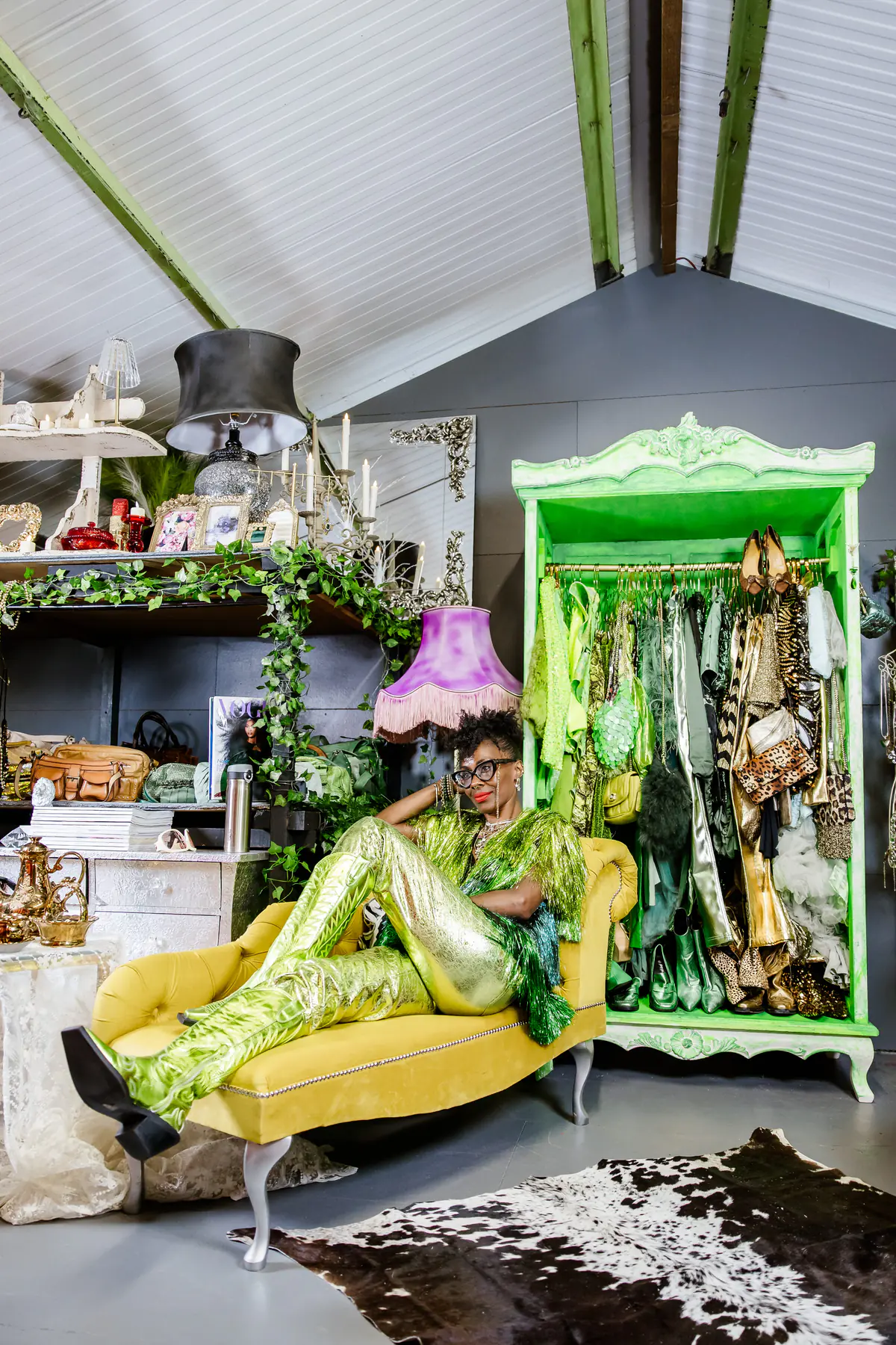 Deborah stretched along the yellow chaise in a gold metallic outfit, the green wardrobe behind.