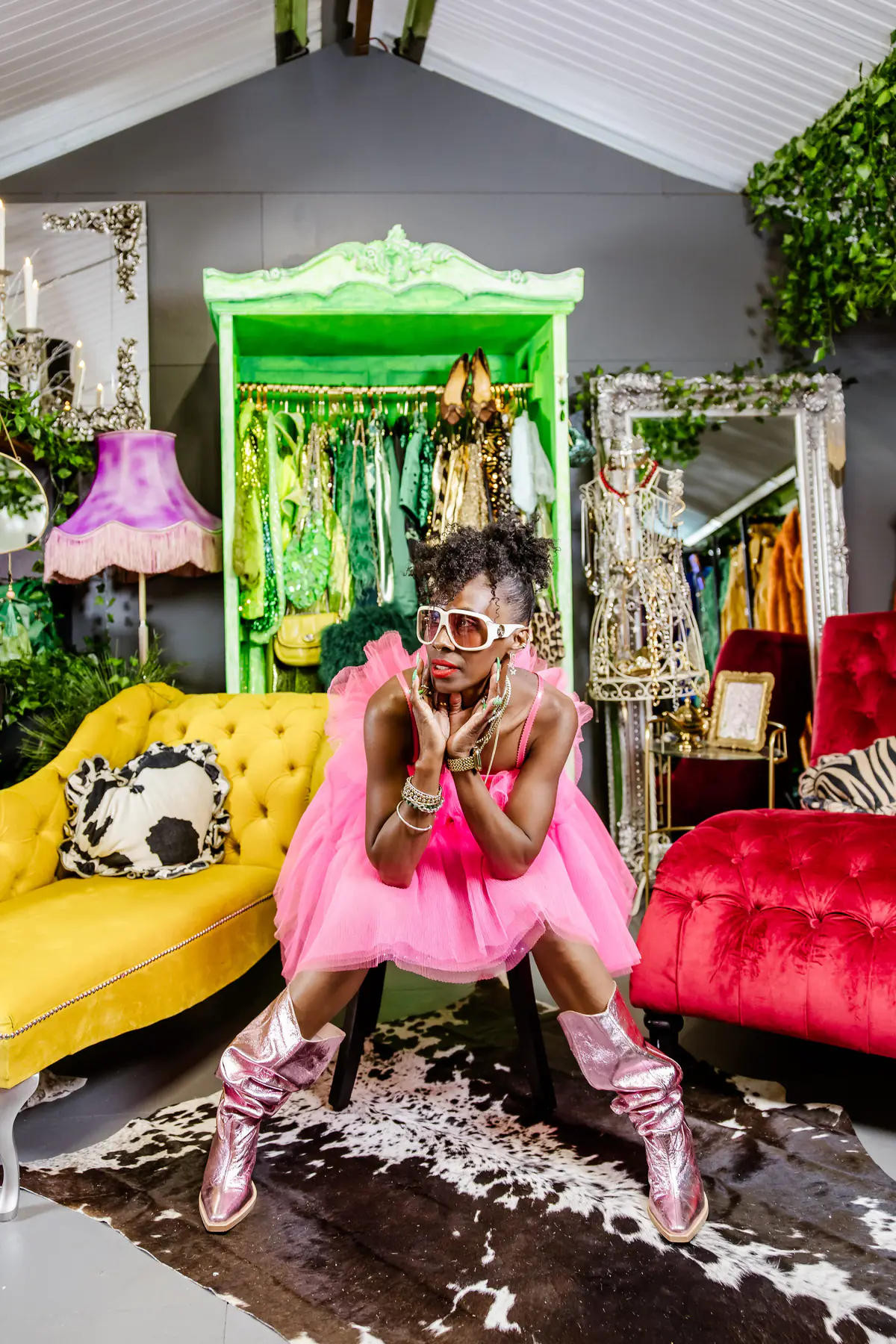 Deborah seated on a low stool in a pink tulle dress and pink glitter boots, hands brought up to her face.